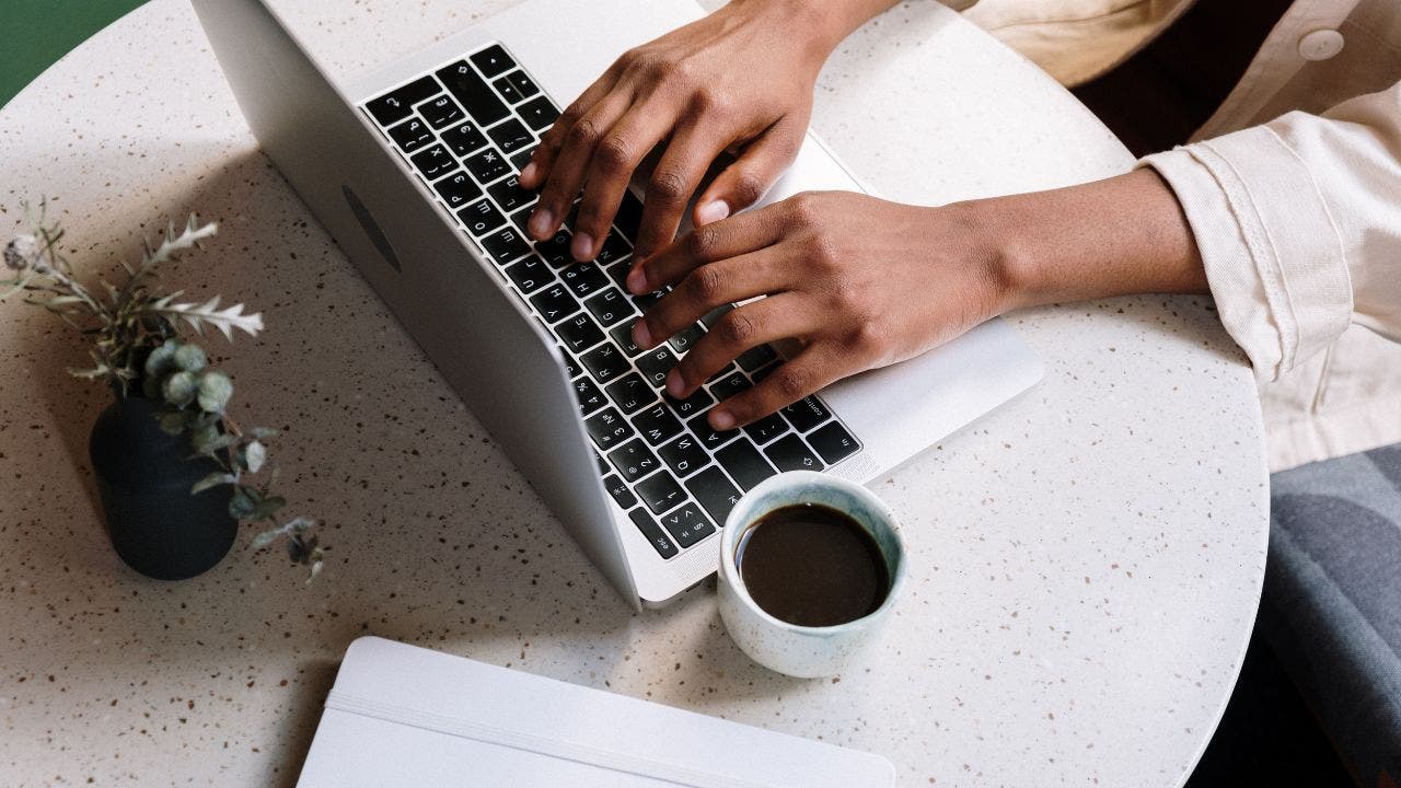 Hands typing on a Mac computer