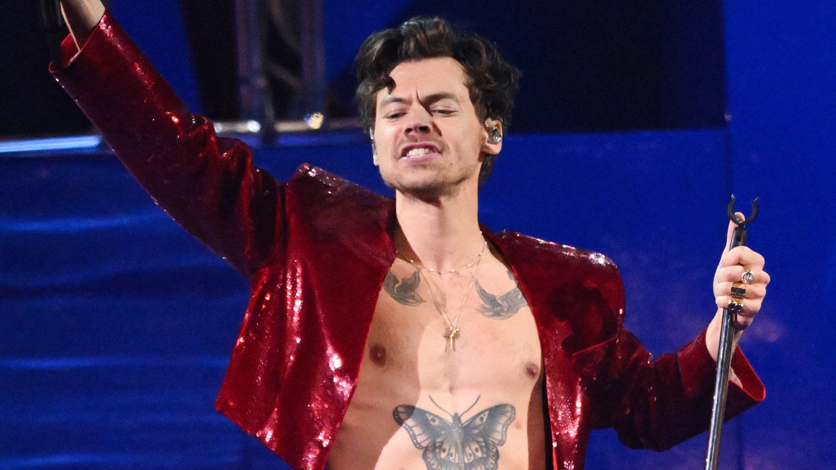 Harry Styles closes his eyes passionately on stage while performing at The BRIT Awards in a sequined jacket and no shirt