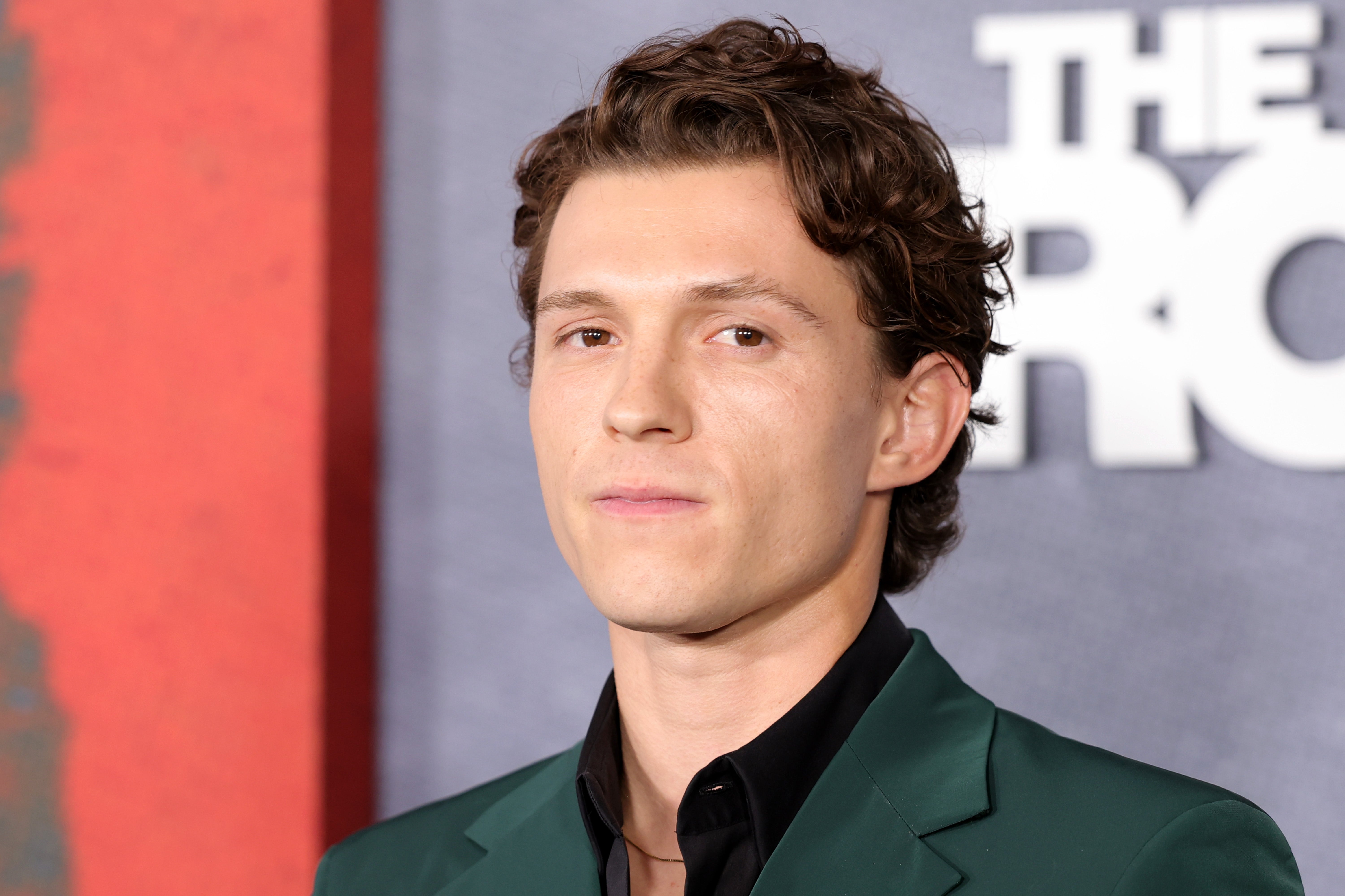 Tom Holland looking serious in a green suit