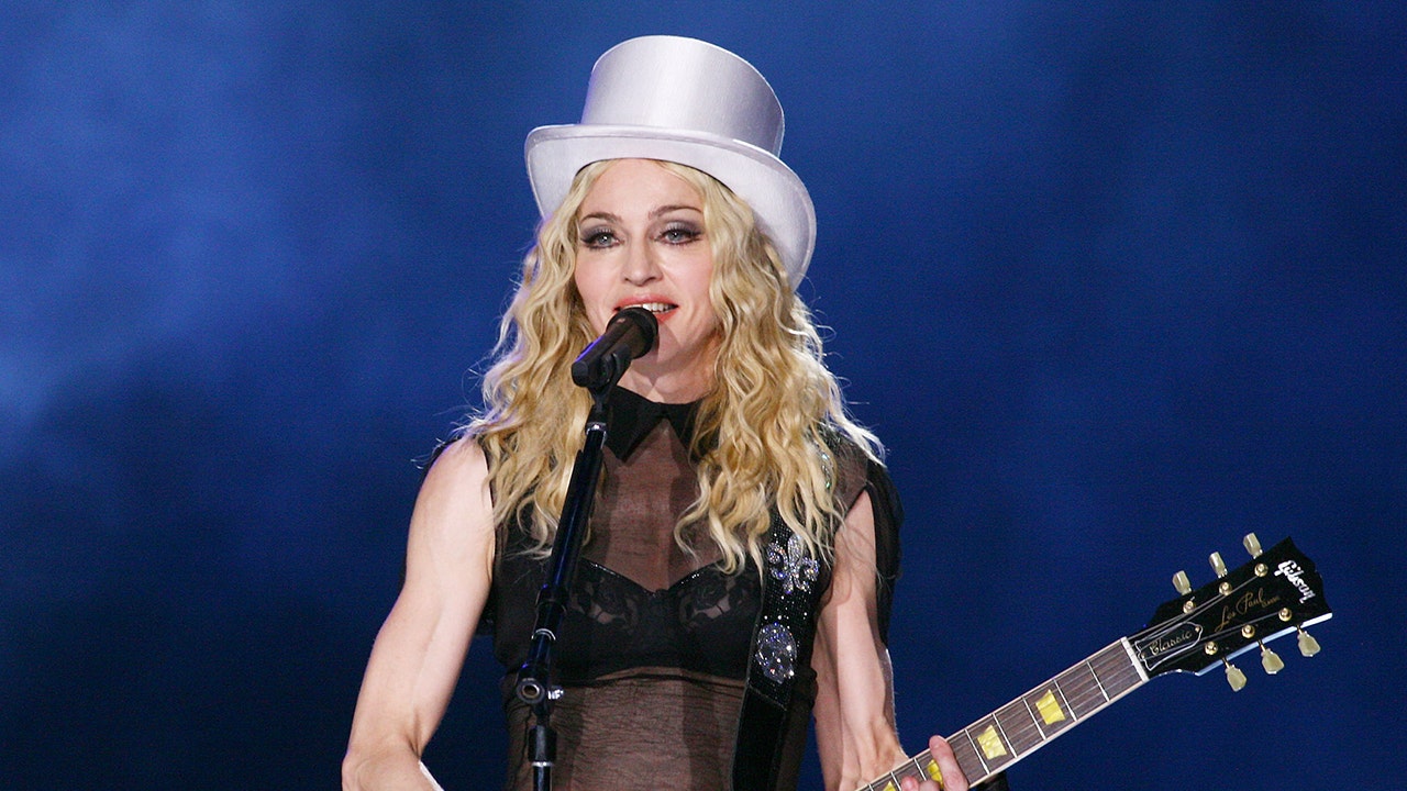 Madonna wears white top hat and strums guitar at concert